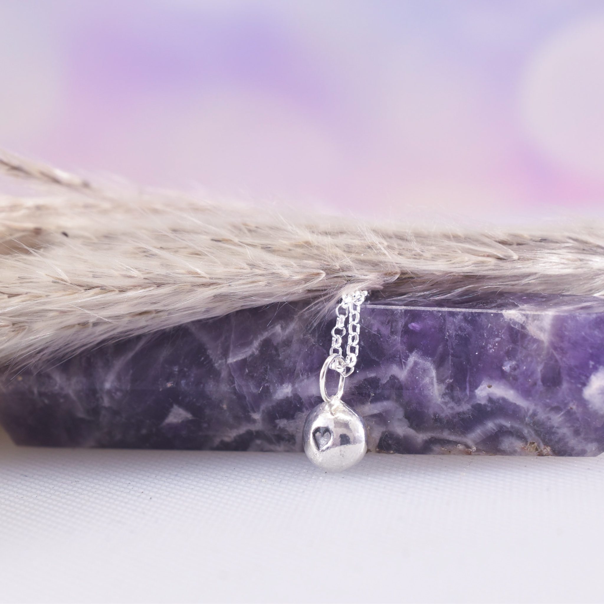 Organic shaped silver pebble necklace with black heart to centre
