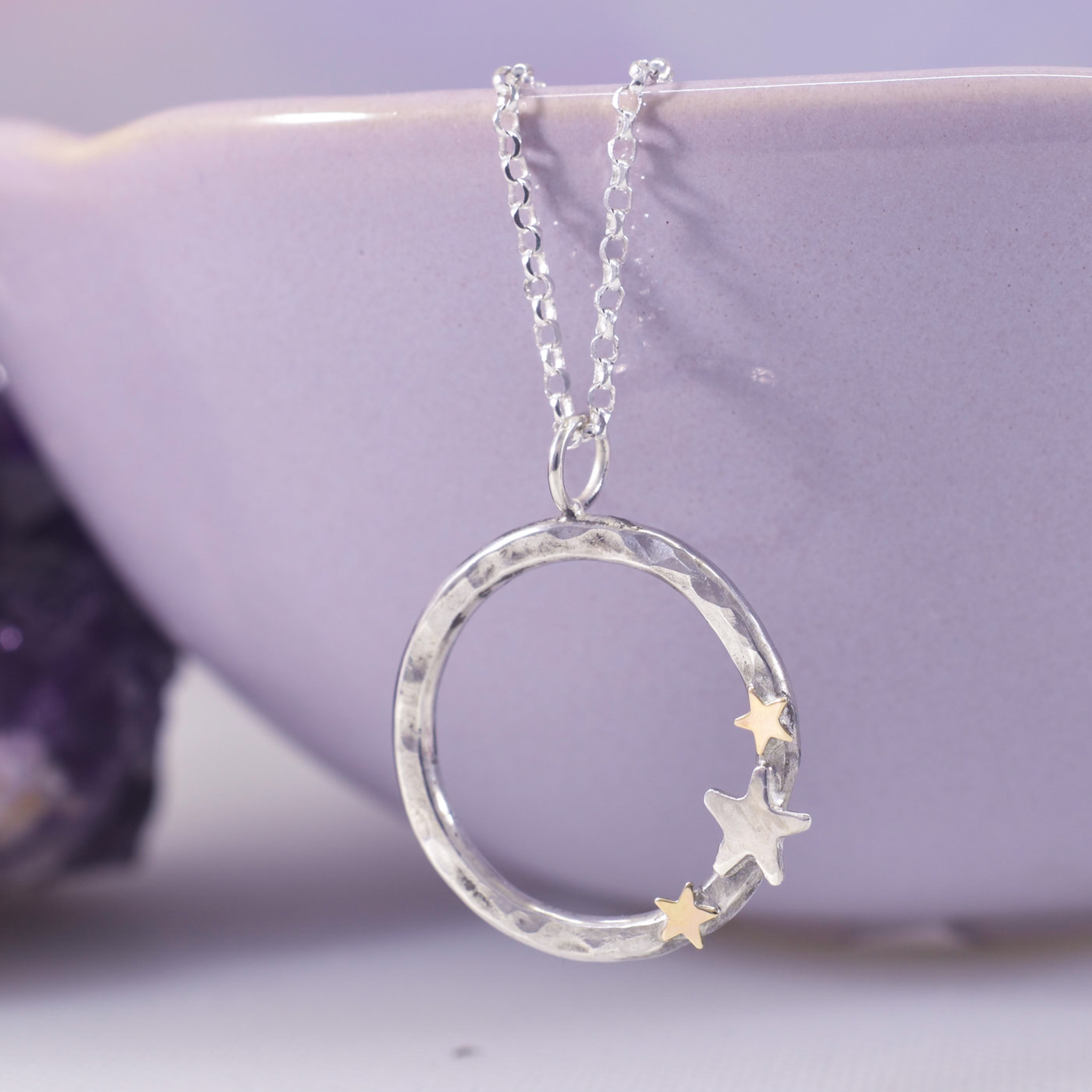 A hoop of hammered silver with gold and silver triple star detail