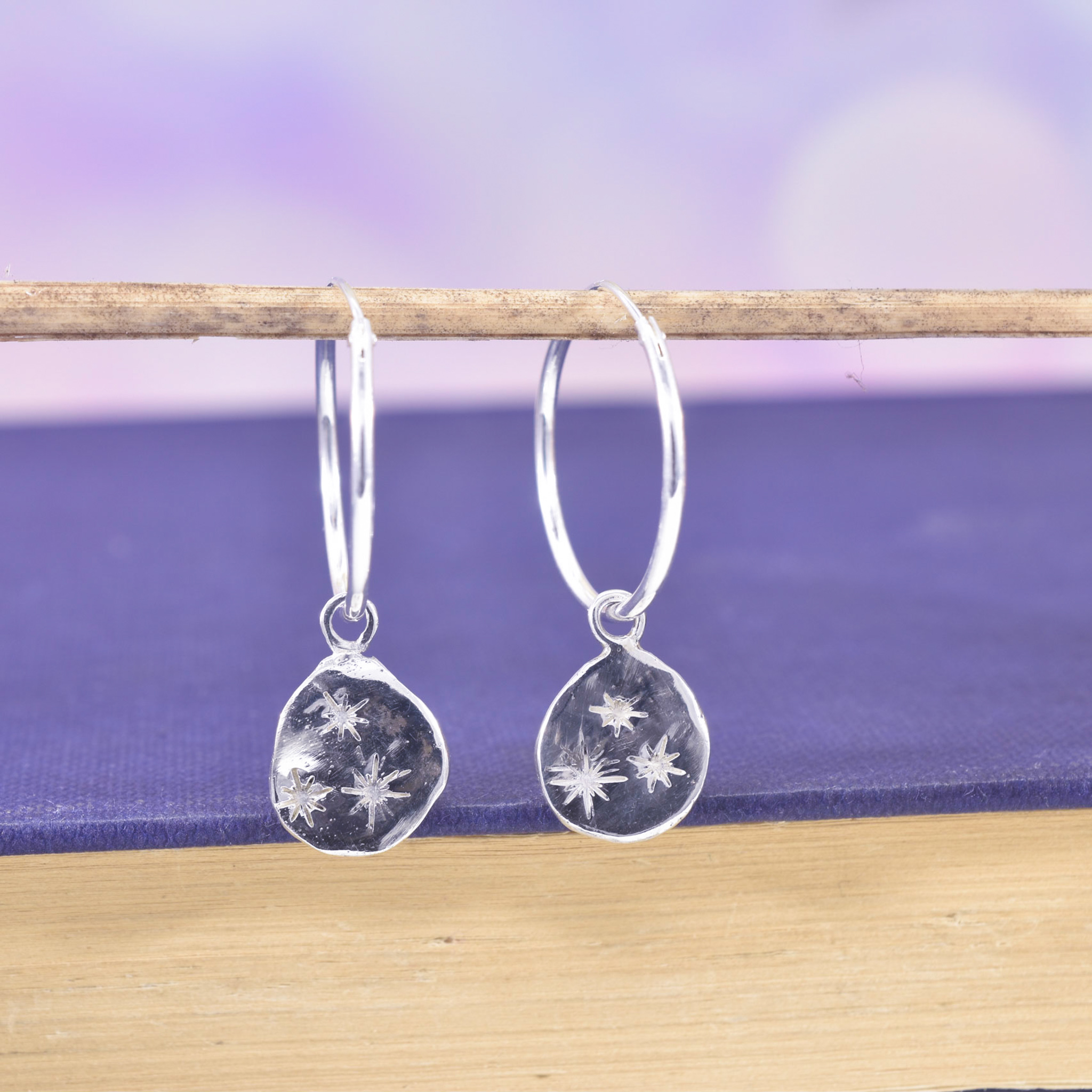 Silver hinged hoop earrings with detachable silver organic star print coins.
