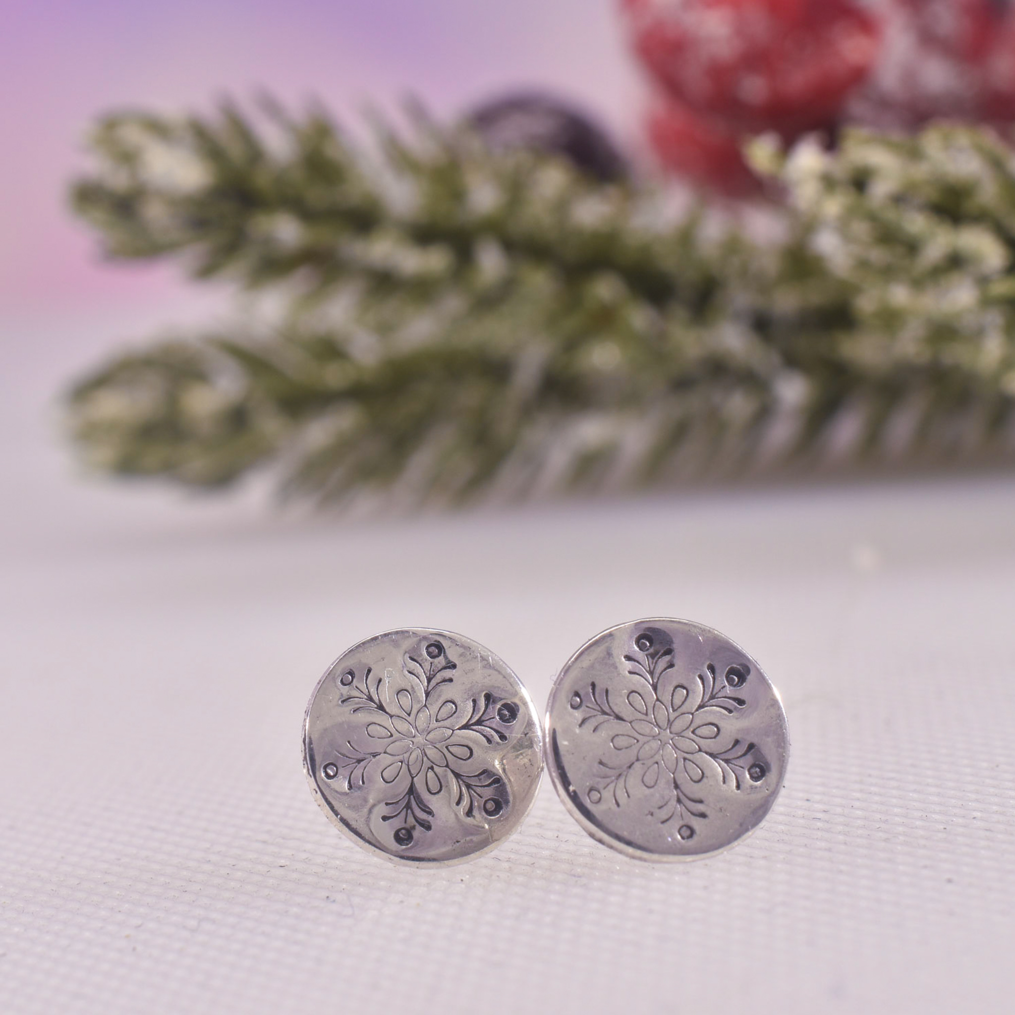 Silver disc earrings with intricate snowflake design highlighted in black enamel