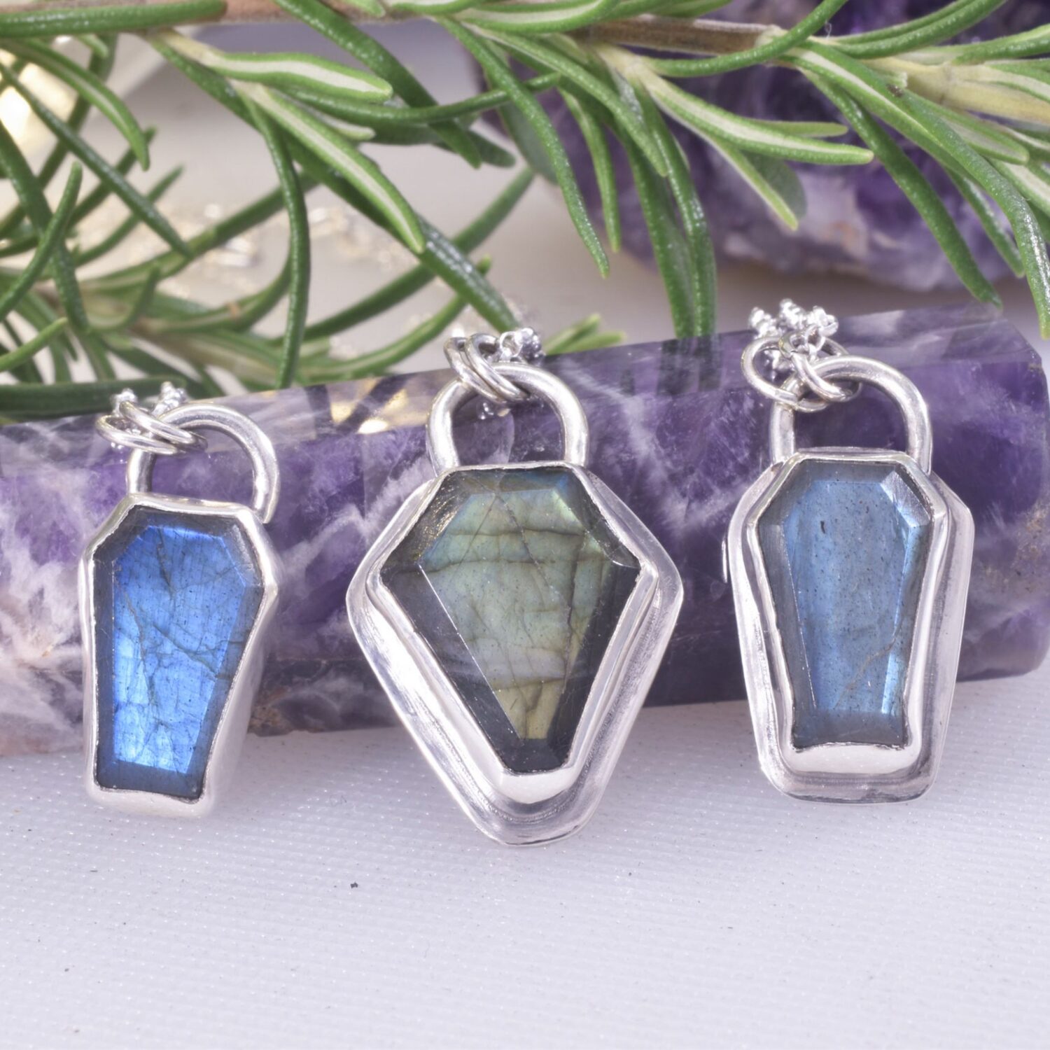 A trio of coffin shaped labradorite gemstone necklaces, set in silver, with stars and moons to the reverse side