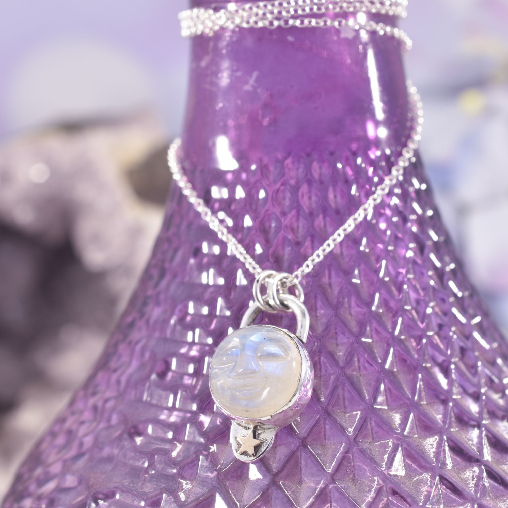 A blue flash rainbow moonstone moon face, set in sterling silver with a tiny gold filled star to the base. the reverse features a hand stamped crescent moon design.