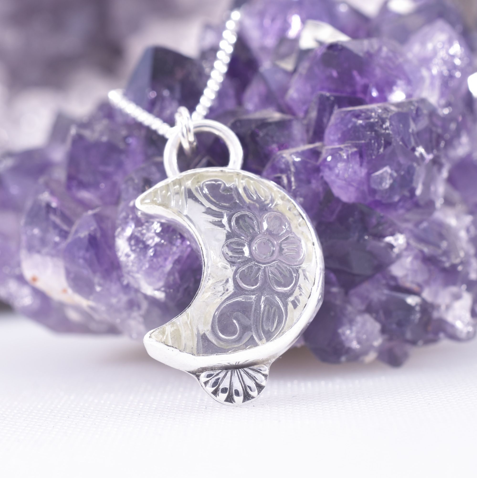A crescent moon of clear quartz, with hand carved flowers to the stone. Set in sterling silver with a crescent moon cut out to the reverse and a solid silver flower fan to the base.