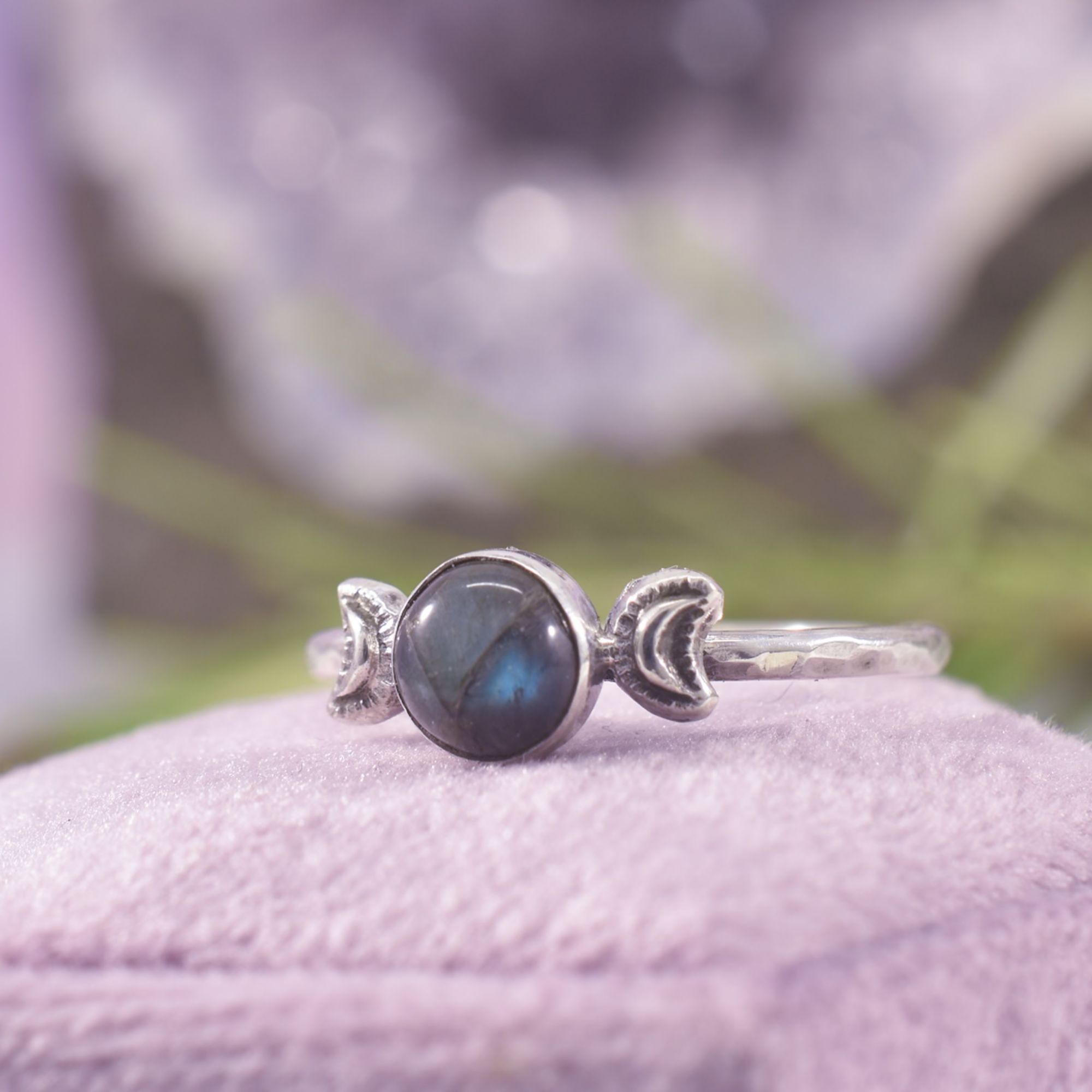 The triple moon phase ring, a full moon in labradorite in the centre, and a solid silver waxing and waning moon to each side, framing the stone. The triple moons sit upon a hammered silver ring band.